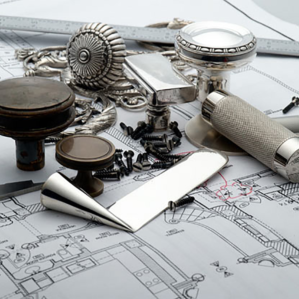 Collection of custom hardware placed on top of architectural drawings and floor plans.